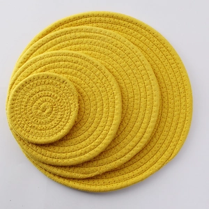 Set of four stacked yellow woven cotton coasters in various sizes for table heat protection
