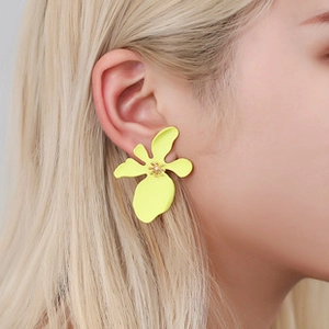 Side view of model wearing large matte yellow floral earrings with pearl center detail