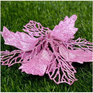 Detailed view of pink glitter artificial Christmas flower on a green grass surface