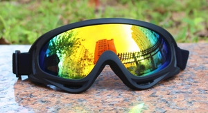 Close-up of X400 polarized ski goggles with rainbow lens on a stone surface