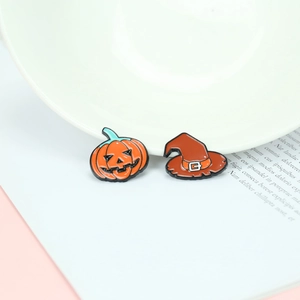Macro shot of Halloween ghost pumpkin and wizard hat enamel pins on a white ceramic bowl