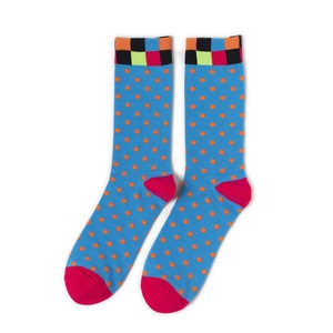 Détail de chaussettes tricotées bleues à pois orange avec revers à carreaux colorés