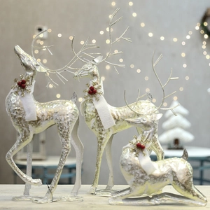 Three elegant iron Christmas reindeer figurines with scarves on a festive bokeh background