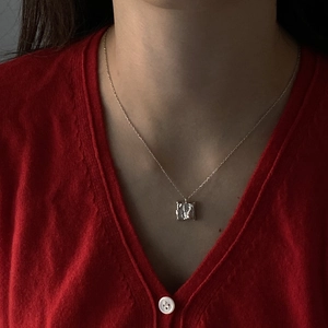 Detailed view of square necklace with irregular hammered texture on female model
