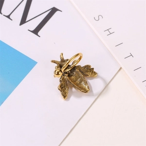 Close-up of vintage gold bee earring with distressed metal texture and U-shaped clip