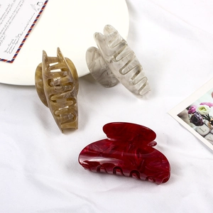 Detail of large marble texture resin hair claws in amber, white, and dark red colors