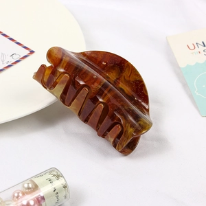 Detail of amber tortoiseshell claw clip with gold glitter on white fabric background