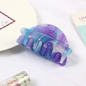 Macro shot of large marble-pattern hair claw clip with purple and blue glitter finish