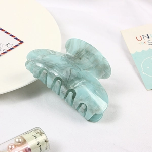 Detailed view of large light blue marble pattern acetate claw clip on white surface