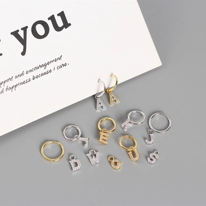 Detailed shot of gold and silver S925 sterling silver hoop earrings with letter charms