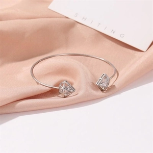Detail of silver hollow triangle bracelet with sparkling zircon on pink silk fabric