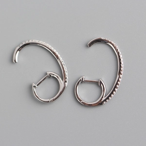 Macro view of curved silver S925 sterling silver earrings with inlaid pavé zircon stones