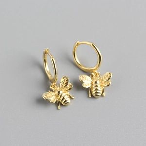 Detailed macro view of gold bee charms on hoop earrings with polished wing texture
