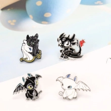 Close-up of four cartoon dragon enamel pins featuring Toothless and Light Fury designs