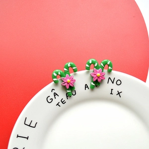 Detail of Christmas candy cane earrings with pink flowers on a green base