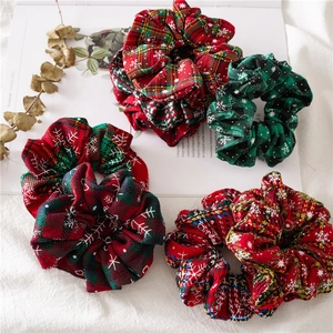 Detail of red and green plaid Christmas hair scrunchies with white snowflake patterns