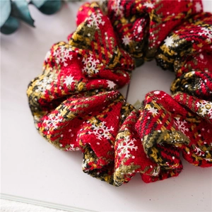 Close-up of red plaid scrunchie with snowflake patterns and festive knit texture