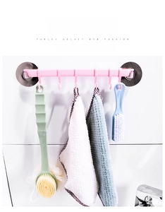Close-up of pink wall-mounted rack with six hooks holding a bath brush and towel