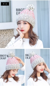 Dettaglio del berretto invernale in maglia con motivi rosa e bianco e un grande pompon
