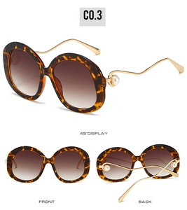 Detail view of tortoiseshell sunglasses with wavy gold temples and pearl accents