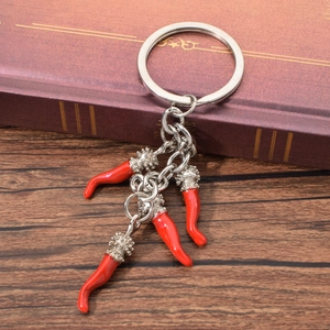 Detailed macro view of silver metal keychain with four vibrant red chili pepper pendants