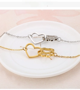 Close-up of interlocking heart and cat paw prints on gold and silver chain bracelets