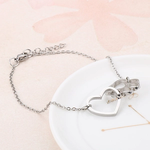 Silver stainless steel bracelet featuring heart and hollow cat paw charms on a white ceramic tray