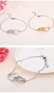 Close-up of heart and cat paw charm bracelets in polished gold and silver finishes