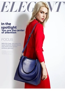Detail of dark blue vintage leather bucket bag held by a model in a red dress