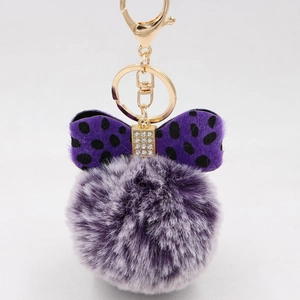Close-up of purple plush ball keychain with a rhinestone studded polka dot bow