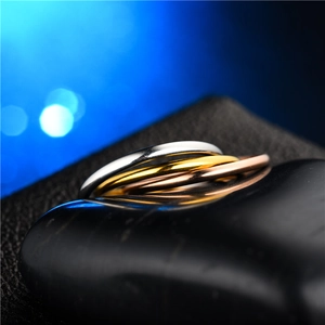 Close-up of three interlocking titanium steel rings in silver, gold and rose gold tones