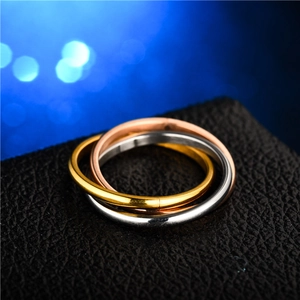 Interlocked gold, silver and rose gold steel rings on a premium black leather texture