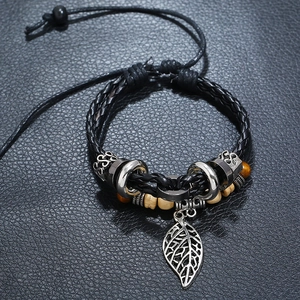 Detail of vintage multilayer beaded leather bracelet with a silver leaf charm and wooden beads