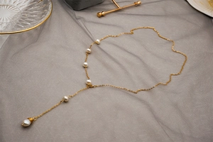 Detail of adjustable Y-shaped gold necklace with white freshwater pearls and wire wrap accents