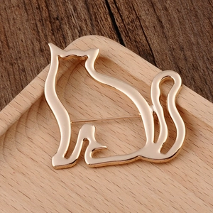 Detailed view of a gold hollow cat brooch on a minimalist wooden display tray