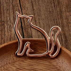 Close-up of rose gold hollow cat brooch with minimalist metal cutout silhouette on wood