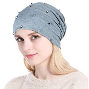 Gros plan d'un bonnet gris en maille orné de clous à pointes métalliques punk