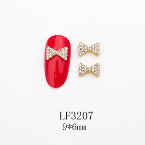 Détail de bijoux d'ongles nœud rouge avec strass et perles sur ongle rouge, 9x6mm
