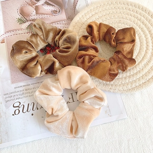 Close-up of velvet scrunchies in champagne and bronze colors on a decorative mat