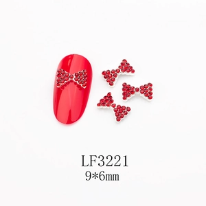 Détail macro de breloques nœud rouge pour nail art avec strass sur fond blanc