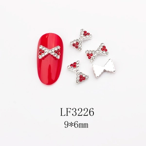 Détail bijou d'ongle nœud 9x6mm avec strass rouges et blancs sur socle en métal