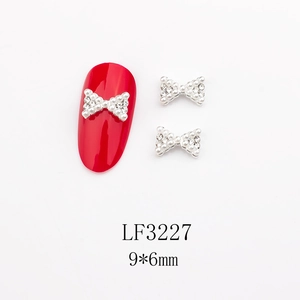Détail d'ongle rouge avec breloque nœud en perle blanche et base en métal argent