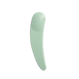 Detail of light green crescent cosmetic spatula for face mask and skin care cream