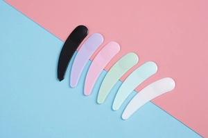 Flat lay of six colorful plastic cosmetic spatulas for cream and mask application
