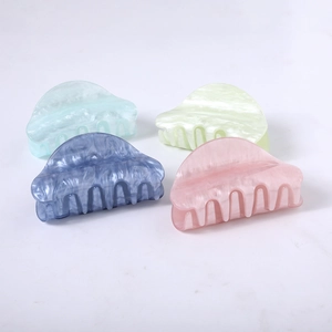 Close-up of acetate hair claws in pastel blue, purple, green and pink on stone