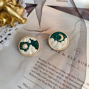 Detail of vintage enamel cloud and moon brooch with pearl accent on retro background