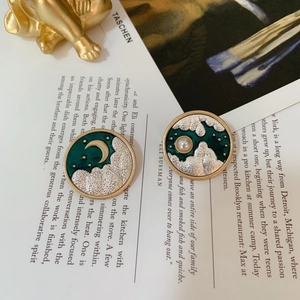 Detailed macro view of vintage round enamel earrings with crescent moon and pearl motifs