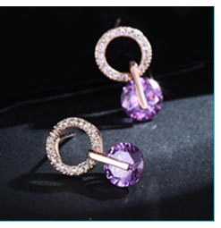 Close-up of rose gold earrings with purple gemstone and sparkling zircon accents