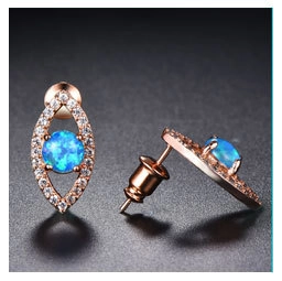 Macro shot of rose gold stud earrings featuring blue opal stones and white zircon accents