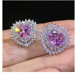 Close-up of heart-shaped earrings with pink zircon stone and double diamond halo